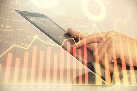 Multi exposure of mans hands holding and using a digital phone and forex graph drawing. Financial...