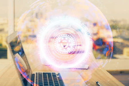 Computer on desktop in office with technology theme hologram. Double exposure. Tech concept.