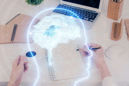 Double exposure of woman's writing hand on background with brain hud. Concept of learning.