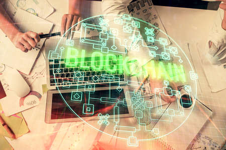 Double exposure of man and woman working together and crypto finance theme hologram. Blockchain...