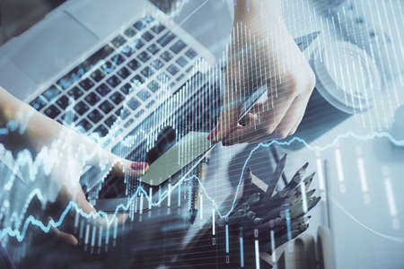 Double exposure of businesswoman hands typing on computer and financial graph hologram drawing....