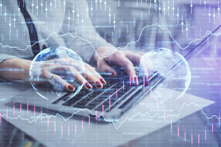 Multi exposure of woman hands typing on computer and financial graph hologram drawing. Stock market...