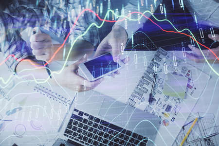 Double exposure of forex graph drawing and man and woman working together holding and using a mobile...