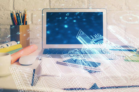 Desktop computer background in office and big town buildings hologram drawing. Double exposure....