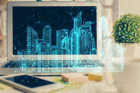 Desktop computer background in office and big town buildings hologram drawing. Double exposure....