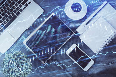 Double exposure of forex chart hologram over desktop with phone. Top view. Mobile trade platform...