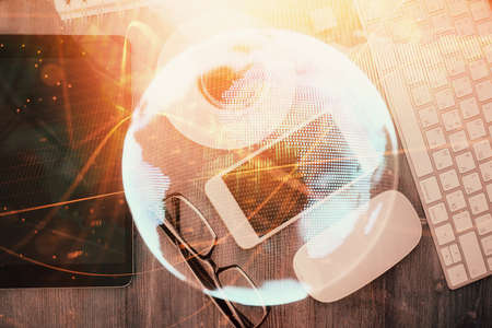 Double exposure of business theme hologram over desktop with phone. Top view. Mobile international...