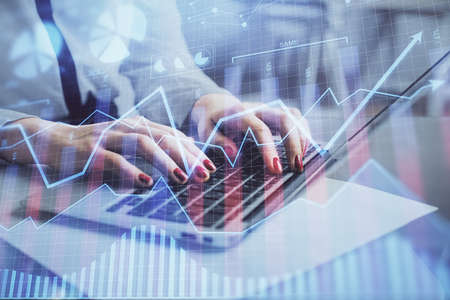 Multi exposure of woman hands typing on computer and financial graph hologram drawing. Stock market...
