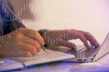 Double exposure of businesswoman hands typing on computer and forex chart hologram drawing....