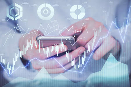 Double exposure of mans hands holding and using a digital device and forex graph drawing. Financial...