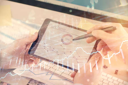 Double exposure of mans hands holding and using a phone and financial chart drawing. Market analysis...