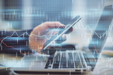 Double exposure of mans hands holding and using a phone and financial graph drawing. Analysis...