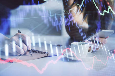 Double exposure of forex graph sketch hologram and woman holding and using a mobile device. Stock...