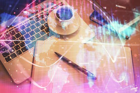 Business theme hologram drawings over computer on the desktop background. Top view. Multi exposure....