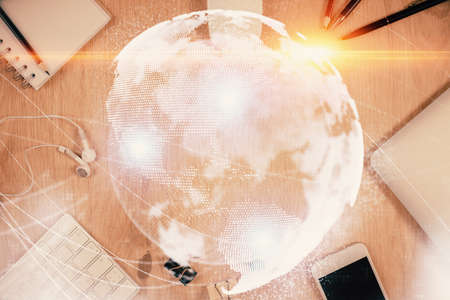 Double exposure of business theme hologram over desktop with phone. Top view. Mobile international...