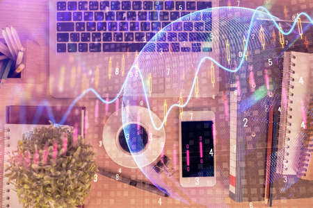 Double exposure of financial graph hologram over desktop with phone. Top view. Mobile trade platform...