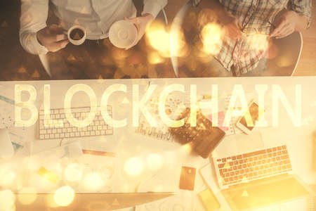 Double exposure of man and woman working together and crypto theme hologram drawing. Computer background. Blockchain concept. Top View.の写真素材