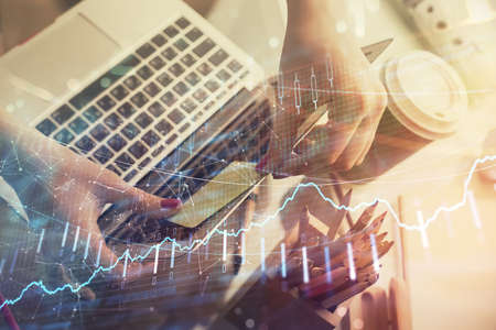 Double exposure of businesswoman hands typing on computer and financial graph hologram drawing. Stock market analysis concept.の写真素材
