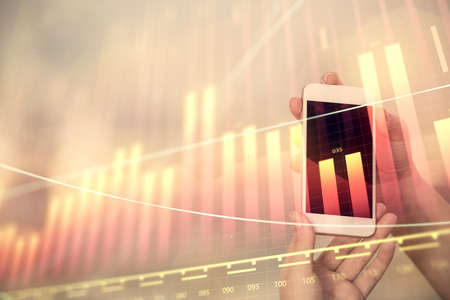 Double exposure of forex chart sketch hologram and woman holding and using a mobile device. Stock market concept.の写真素材