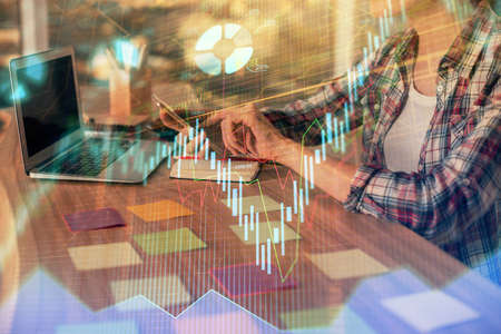 Double exposure of businesswoman hands typing on computer and forex graph hologram drawing....