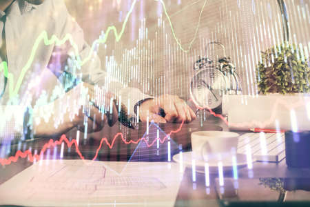Double exposure of mans hands holding and using a phone and financial graph drawing. Analysis concept.の写真素材
