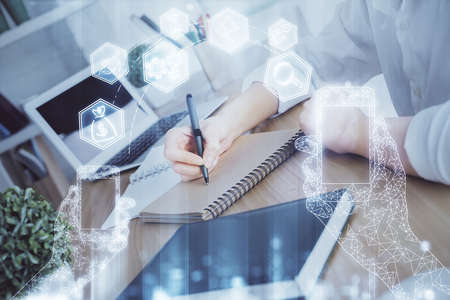 Tech theme hologram over womans hands taking notes background. Concept of hightech. Double exposure