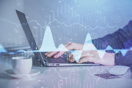 Double exposure of businesswoman hands typing on computer and forex graph hologram drawing....