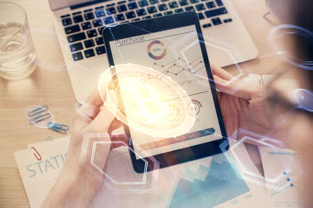 Double exposure of mans hands holding and using a phone and crypto currency blockchain theme...