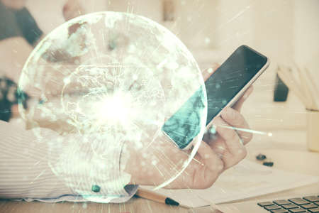 Double exposure of mans hands holding and using a phone and international business theme drawing.