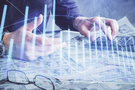 Double exposure of mans hands holding and using a digital device and forex graph drawing. Financial market concept.の写真素材