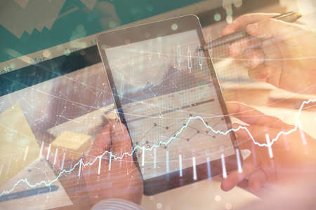 Double exposure of mans hands holding and using a phone and financial chart drawing. Market analysis concept.の写真素材
