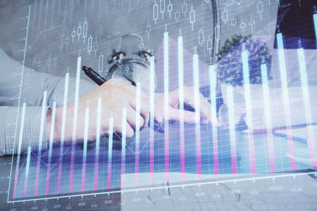 Double exposure of mans hands holding and using a phone and financial graph drawing. Analysis...