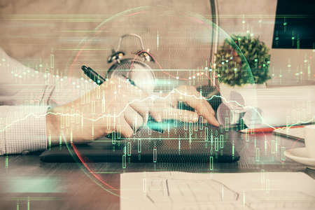 Double exposure of mans hands holding and using a phone and financial graph drawing. Analysis...