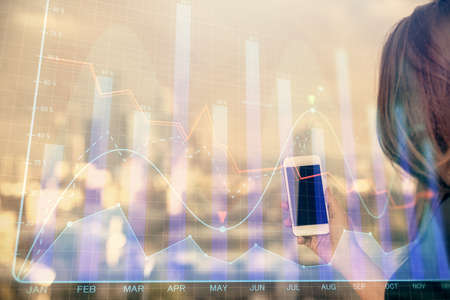 Double exposure of forex chart sketch hologram and woman holding and using a mobile device. Stock...