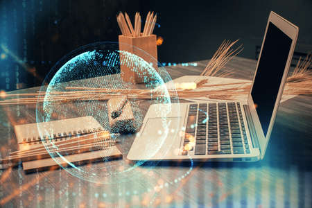Double exposure of desktop with computer and world map hologram. International data network concept.の写真素材