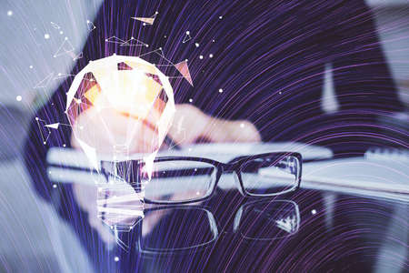 Bulb hologram over hands taking notes background. Concept of idea. Double exposure