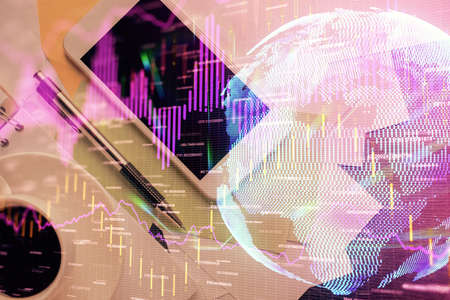Multi exposure of forex graph hologram over desktop with phone. Top view. Mobile trade platform...