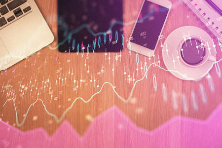 Double exposure of financial chart hologram over desktop with phone. Top view. Mobile trade platform...