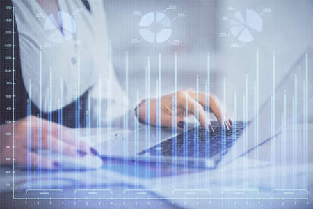 Double exposure of businesswoman hands typing on computer and forex graph hologram drawing....