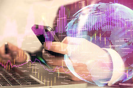 Multi exposure of mans hands holding and using a digital phone and forex graph drawing. Financial...