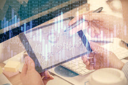 Double exposure of mans hands holding and using a phone and financial chart drawing. Market analysis...