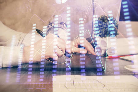 Double exposure of mans hands holding and using a phone and financial graph drawing. Analysis...