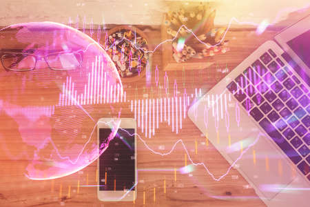 Double exposure of financial graph hologram over desktop with phone. Top view. Mobile trade platform...