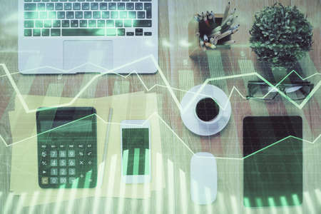 Double exposure of forex chart hologram over desktop with phone. Top view. Mobile trade platform...