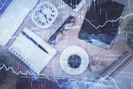 Double exposure of financial chart hologram over desktop with phone. Top view. Mobile trade platform...