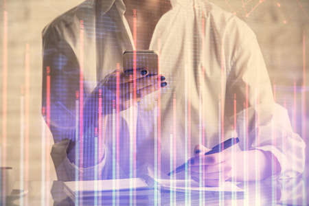 Double exposure of financial graph sketch hologram and woman holding and using a mobile device....