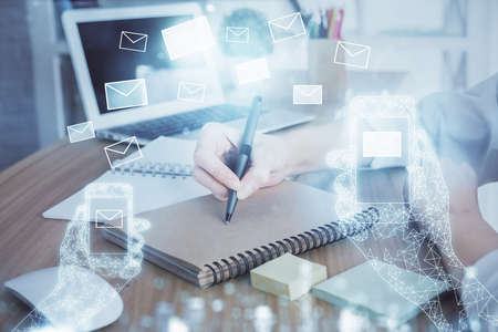 E-mail abstract envelop drawing over hands taking notes background. Concept of electronic mail. Double exposureの写真素材