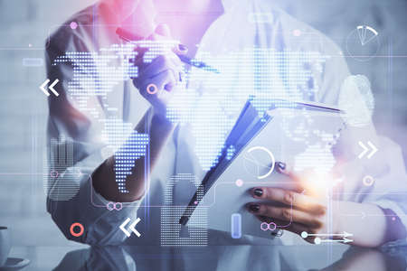Double exposure of hands making notes with world map hologram and data theme icons. Concept of...