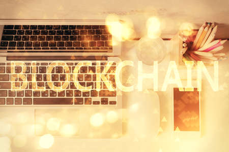 Blockchain theme hologram drawings over computer on the desktop background. Top view. Multi...