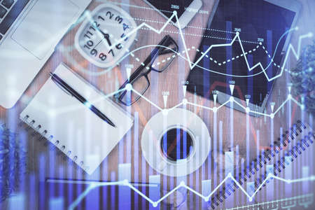 Double exposure of financial chart hologram over desktop with phone. Top view. Mobile trade platform...